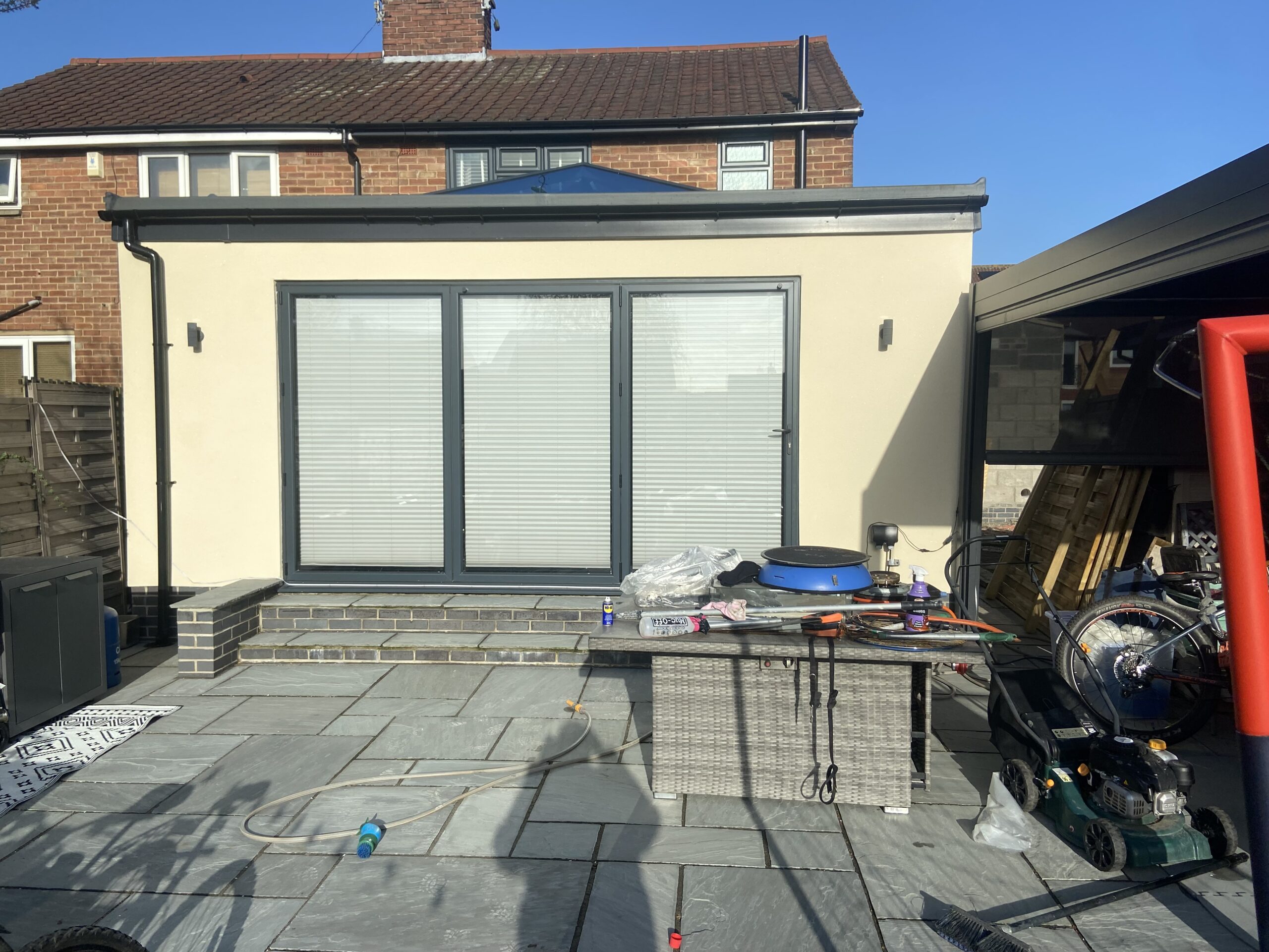 Cream-coloured monocouche-rendered house extension in York with glazed doors and patio materials in front.
